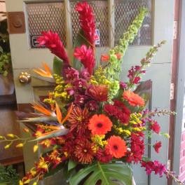 Tropical flower arrangement with orange gerberas and red blooms in a vase