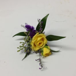 Yellow rose boutonniere with purple filler and green leaves
