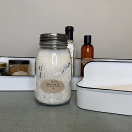 Bath salts jar with assorted spa gift items in white trays