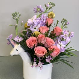 Pink roses and lavender flowers in a unicorn-shaped vase