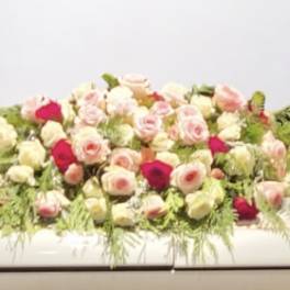Low arrangement of pink and white roses with greenery