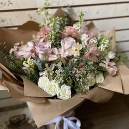 Bouquet of blush and white roses with pale pink flowers in brown paper