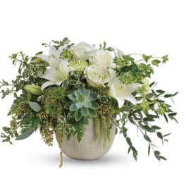 White lilies and roses in a ceramic vase with trailing greenery
