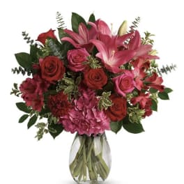 Bouquet of pink lilies and red roses in a clear glass vase