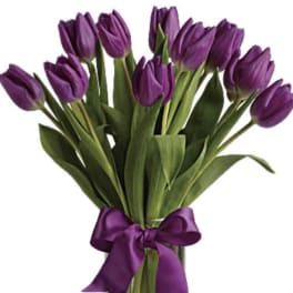 Purple tulip bouquet in a clear glass vase with a purple ribbon