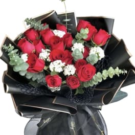 Bouquet of red roses with white filler flowers wrapped in black paper
