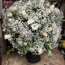 Large white floral arrangement with small pink roses in a black vase