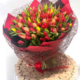 Large bouquet of red, pink, peach, and yellow tulips wrapped in red and black paper