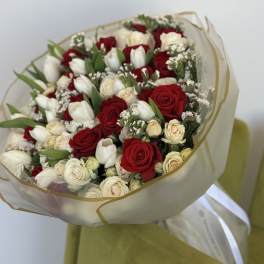 Bouquet of red and white roses with white tulips wrapped in sheer paper
