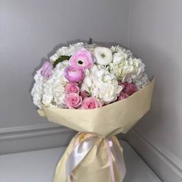 Bouquet of pink and white flowers wrapped in beige paper with ribbon