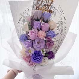 Bouquet of purple and pink roses wrapped in white paper