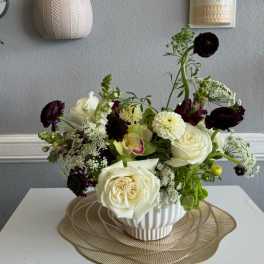 White and dark burgundy floral arrangement in a ribbed white vase