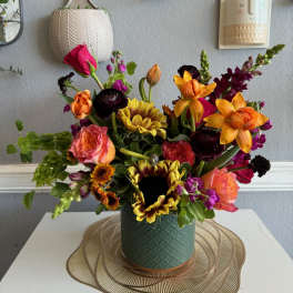Colorful mixed bouquet in a green vase with sunflowers, roses, and tulips