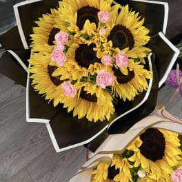Bouquet of sunflowers with small pink carnations wrapped in black paper