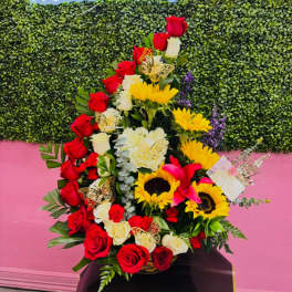 Tall floral arrangement with red and white roses, sunflowers, and pink lilies