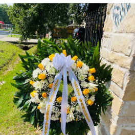 Standing funeral wreath of yellow roses and white flowers with a ribbon