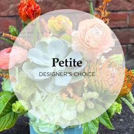 Mixed bouquet with pale hydrangea, ranunculus, and protea in a blue container