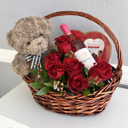 Basket with red roses, a teddy bear, and chocolates
