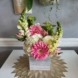 Pink and white flowers arranged in a square gray vase