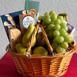 Wicker basket filled with grapes, pears, and boxed chocolates