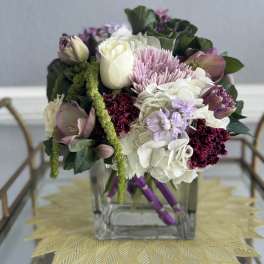 Mixed bouquet in a clear square vase with white, pink, and purple blooms