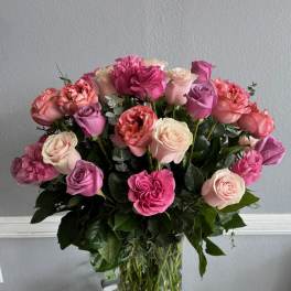 Pink and lavender roses arranged in a clear glass vase