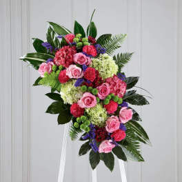 Standing floral spray with pink roses, hydrangeas, and mixed blooms on an easel