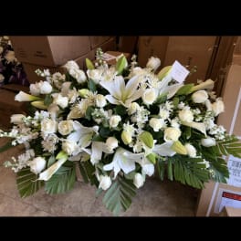 Large white floral casket spray with lilies and roses
