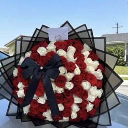 Bouquet of red and white roses with a black ribbon and envelope topper