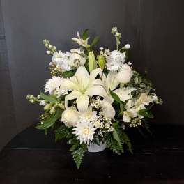 White lilies and roses arranged in a low vase with white daisies