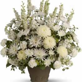 White floral arrangement in a dark vase with tall spires and round blooms