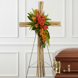 Floral cross on an easel beside a casket