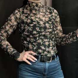 Person wearing a black floral long-sleeve top and blue jeans