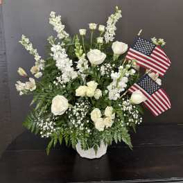 White floral arrangement with two American flags in a white vase