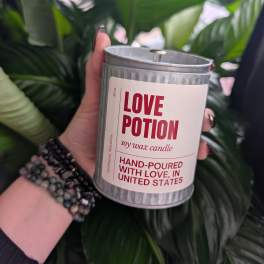 Handheld soy wax candle in a metal tin labeled Love Potion