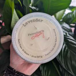 Hand holding a lavender-scented candle in a clear plastic cup