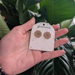 Hand holding daisy-shaped stud earrings on a card