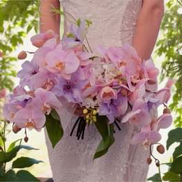 Bride holding a cascading bouquet of pink and lavender orchids