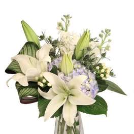 White lilies and pale hydrangeas in a clear glass vase