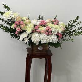 Large white and pink floral arrangement in a brown container on a stand