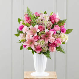 Pink lilies and roses arranged in a white vase
