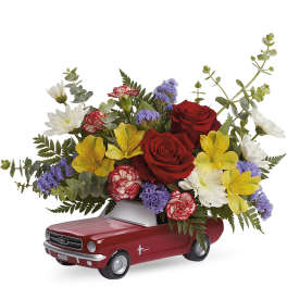 Bouquet of red roses, yellow alstroemeria, and daisies in a red toy car container