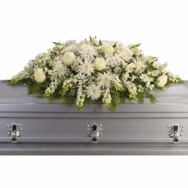 White floral casket spray with mixed blooms on a silver casket