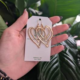 Gold heart-shaped earrings on a display card held in a hand