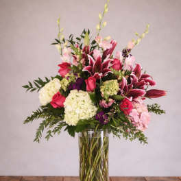 Tall bouquet of pink lilies, roses, and hydrangeas in a glass vase