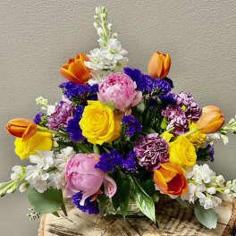 Colorful mixed bouquet in a glass vase with roses, tulips, and white blooms