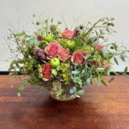 Pink roses in a low bowl with greenery and green apples