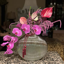 Pink orchids and anthuriums in a ribbed glass vase