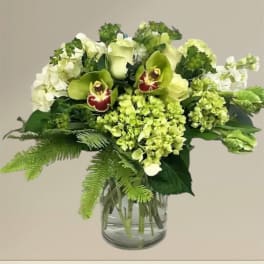 Green and white floral arrangement in a glass vase