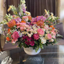 Large mixed bouquet in a white vase with pink, orange, and white blooms